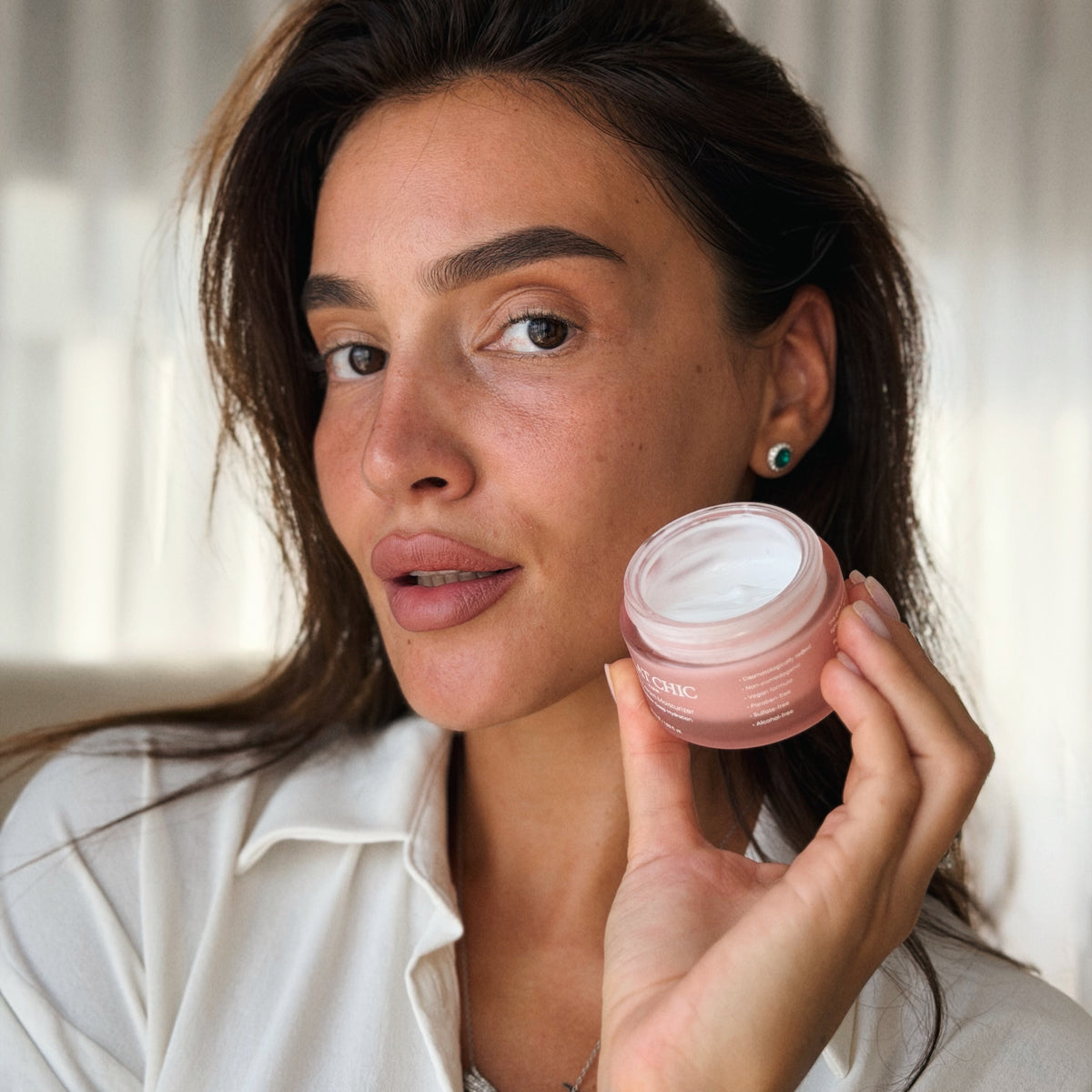 Glow Cream Moisturizer kavanozunu yüzüne yaklaştıran kadın